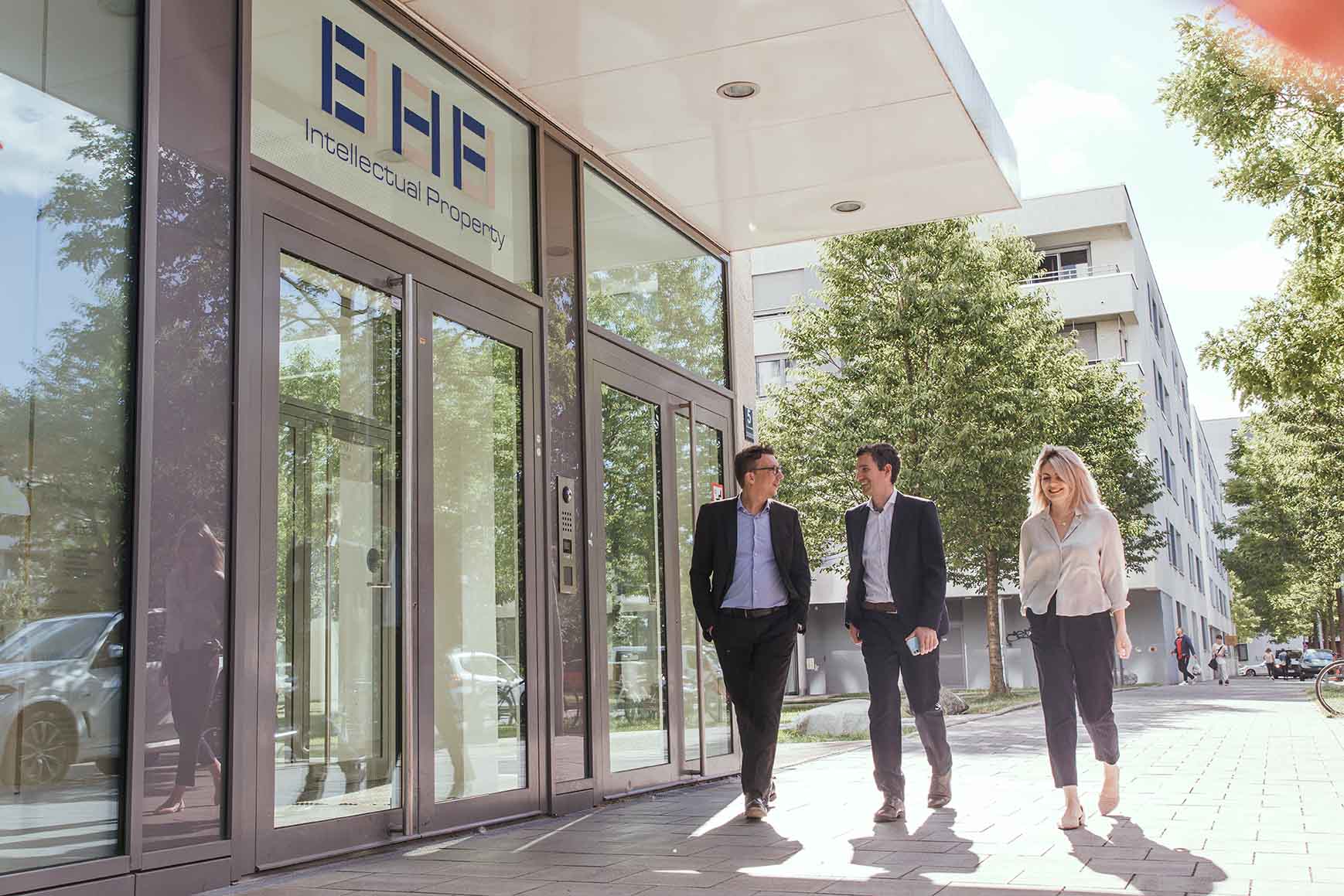 Partner und Mitarbeiterin von EHF gemeinsam vor dem Gebäude der EHF Patentanwaltskanzlei München